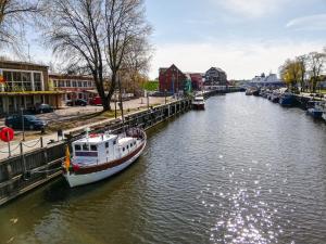 a boat is docked on a river in a city at Historical boat Tu vėjo paklausk in Klaipėda