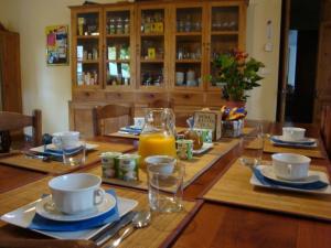 een houten tafel met borden en bekers en een fles sinaasappelsap bij Le village-hôtes in Sainte-Vallière