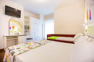 a white bedroom with a bed and a tv at Hotel Adelphi in Riccione