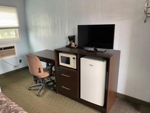 a room with a desk with a microwave and a tv at All Seasons Motel in Port Elgin