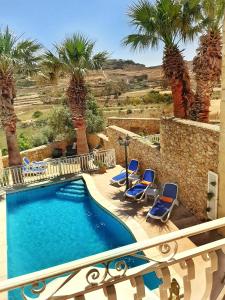 basen z krzesłami i palmami na balkonie w obiekcie Blossom Farmhouses w mieście Għasri