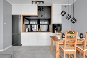 a kitchen with white cabinets and a black refrigerator at Maximus Apartment by TriApart in Gdańsk