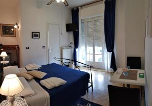 1 dormitorio con cama azul, mesa y ventana en Le Midi Versilia, en Lido di Camaiore