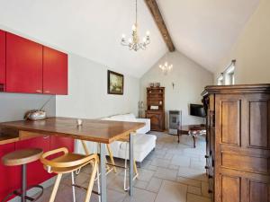 cocina con armarios rojos, mesa y sillas en Charming Holiday Home in Geetbets with Terrace, en Geetbets