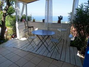 een tafel en stoelen op een veranda met uitzicht op de oceaan bij CASA PENTONE in Cervione