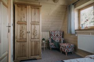 a room with a chair and a cabinet and a window at Szałas Kosówka in Witów