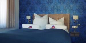 a blue bedroom with a large bed with pillows at Arthotel Nagold in Nagold