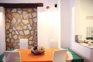 uma mesa de jantar com cadeiras e uma parede de pedra em Daniela House em Santa Teresa di Riva