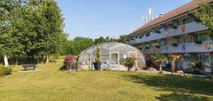 a building with a glass greenhouse next to a park at Brit Hotel Confort Nancy Lunéville in Lunéville