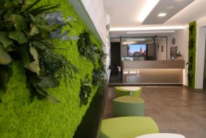 a room with a green wall with a table and chairs at Hotel Nederland in Caorle