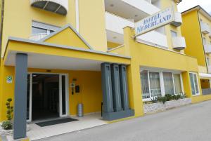 a yellow building with a sign that reads hotel national mall at Hotel Nederland in Caorle