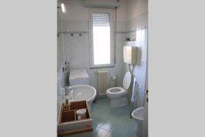 uma casa de banho com um lavatório, um WC e uma janela. em Appartamento delle Vele em Bellaria-Igea Marina