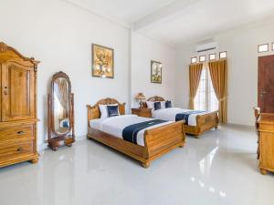 1 dormitorio con 2 camas y espejo en SUPER OYO Collection O 3468 Ndalem Gusti Ayu, en Yogyakarta