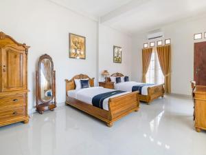 a bedroom with two beds and a mirror at Super OYO Collection O 3468 Ndalem Gusti Ayu in Yogyakarta