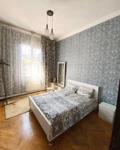una camera con un letto in una stanza con carta da parati di Eka Guest House a Batumi