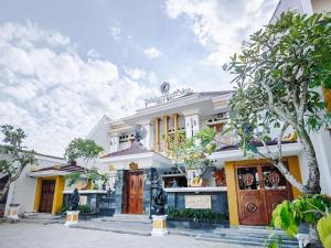 a white house with a tree in front of it at SUPER OYO Collection O 3468 Ndalem Gusti Ayu in Yogyakarta