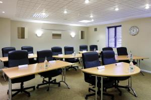 uma sala de conferências com mesas e cadeiras e um relógio em ibis Preston North em Preston