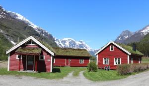 twee rode schuren met gras op het dak voor de bergen bij Trollbu Aabrekk gard in Briksdalsbre