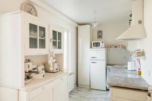 a kitchen with white cabinets and a white refrigerator at Vintage Lounge studio by the sea in Liepaja in Liepāja