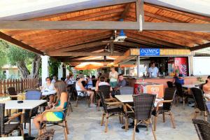 a group of people sitting at tables in a restaurant at Andreas House in Dassia