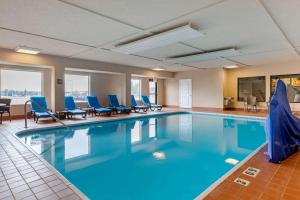 una piscina en una habitación de hotel con sillas azules en Comfort Suites South Haven near I-96, en South Haven