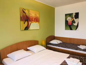 a bedroom with two beds and two paintings on the wall at Vila Timona in Eforie Nord