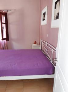 a bed with purple sheets in a room at Kasteli House in Spetses