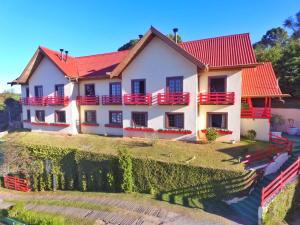 une maison avec un toit rouge sur une colline dans l'établissement Pousada AlpenRose, à Campos do Jordão