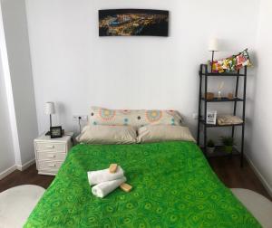 a bedroom with a green bed with a stuffed animal on it at Perla Lagunillas Málaga in Málaga