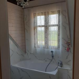 a white bath tub in a bathroom with a window at Malowniczy Zakątek w Dercu in Derc