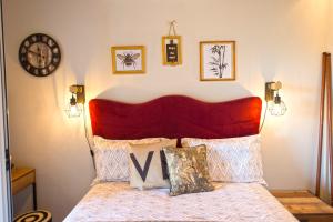 1 cama con cabecero rojo y reloj en la pared en Salty Breeze Experience vs Olive Flavor Sensation at Porto Cheli, en Porto Heli
