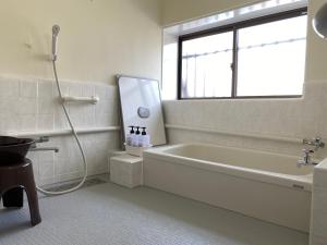 a bathroom with a bath tub and a window at Guest House Enishi in Toyama