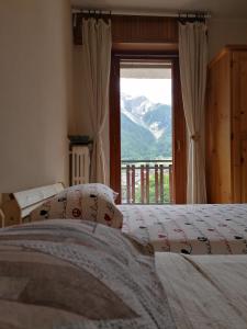 a bedroom with two beds and a window with a view at Courma House in Courmayeur