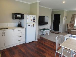a kitchen with a white refrigerator and a table with chairs at The Practice Fairway in Tauranga
