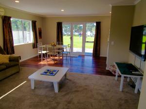 ein Wohnzimmer mit einem Sofa und einem Tisch in der Unterkunft The Practice Fairway in Tauranga