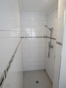 Baño de azulejos blancos con ducha y drenaje en The Practice Fairway, en Tauranga