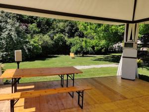 a wooden table and a bench under a tent at Agriturismo La Sophora in Montegaldella