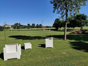 tres sillas blancas sentadas en el césped en un campo en Agriturismo La Sophora, en Montegaldella