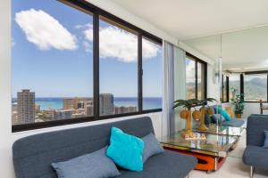 sala de estar con sofá azul y ventanas grandes en 2 Bedroom Penthouse w/Ocean Views, en Honolulu