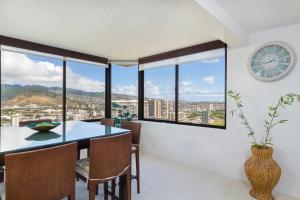a dining room with a table and a clock on the wall at 2 Bedroom Penthouse w/Ocean Views in Honolulu
