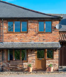 a brick house with a wooden door and windows at The Windmill Cottage in Melton Mowbray
