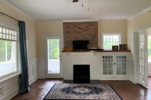 a living room with a fireplace and two windows at Renovated 1928 bungalow on a former asylum campus in Milledgeville