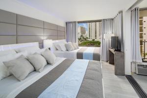 a hotel room with two beds and a television at Waikiki Banyan Modern One Bedroom Free Parking in Honolulu