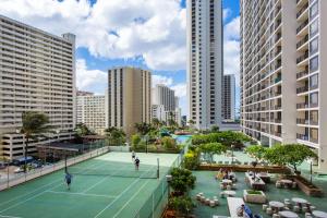 two people playing tennis on a tennis court in a city at Waikiki Banyan Modern One Bedroom Free Parking in Honolulu