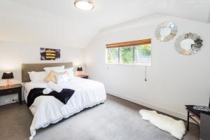 a white bedroom with a bed and a window at Lakeside Luxury with Spa in Queenstown