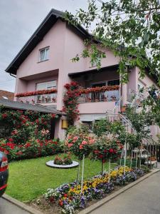 une maison rose avec des fleurs devant elle dans l'établissement Apartman Vesna, à Bjelovar