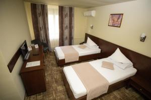 a hotel room with two beds and a television at Hotel Select Slobozia in Slobozia