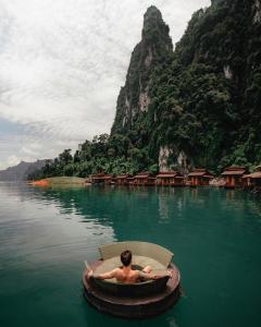 
a man sitting on a boat in the middle of a river at Panvaree Resort in Ban Chieo Ko

