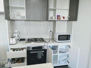 cocina pequeña con fogones y microondas en Luxury 3-bed 2-bath, balcony, with pool included, NO PARTIES! en Sídney