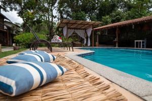 a swimming pool with pillows and a bench next to it at Trancoso Pousada in Trancoso